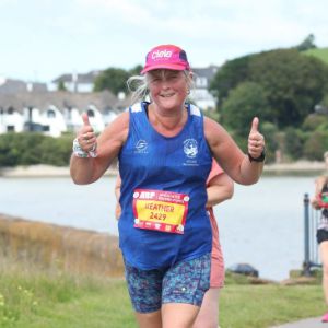 Heather Morgan smiling and giving two thumbs up while running a race